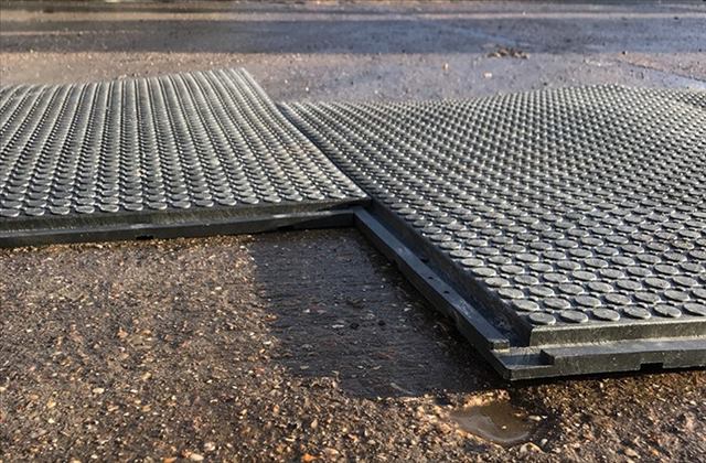 Close-up of interlocking rubber mats on a wet surface, showing their textured design for grip.