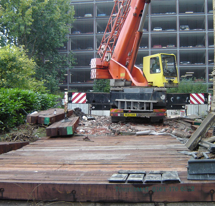 orange crane at a building site using timber ground support