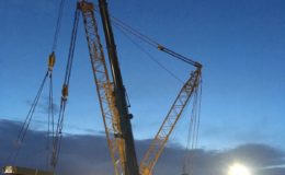cranes lowering supplies at night under floodlight
