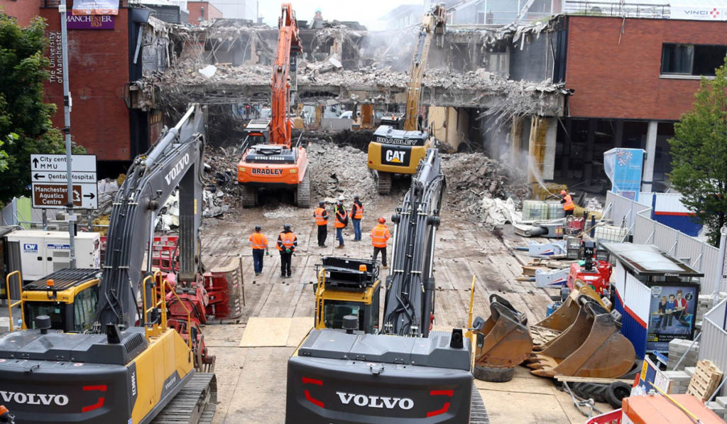 multiple machines and workers stood on matting at manchester university demolition site
