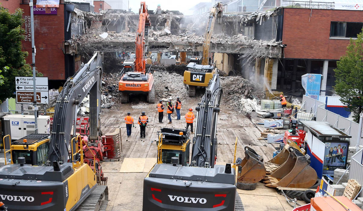 multiple machines and workers stood on matting at manchester university demolition site
