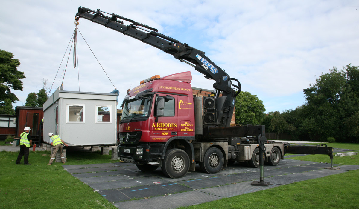 crane using crane mats for support while moving portacabins into place