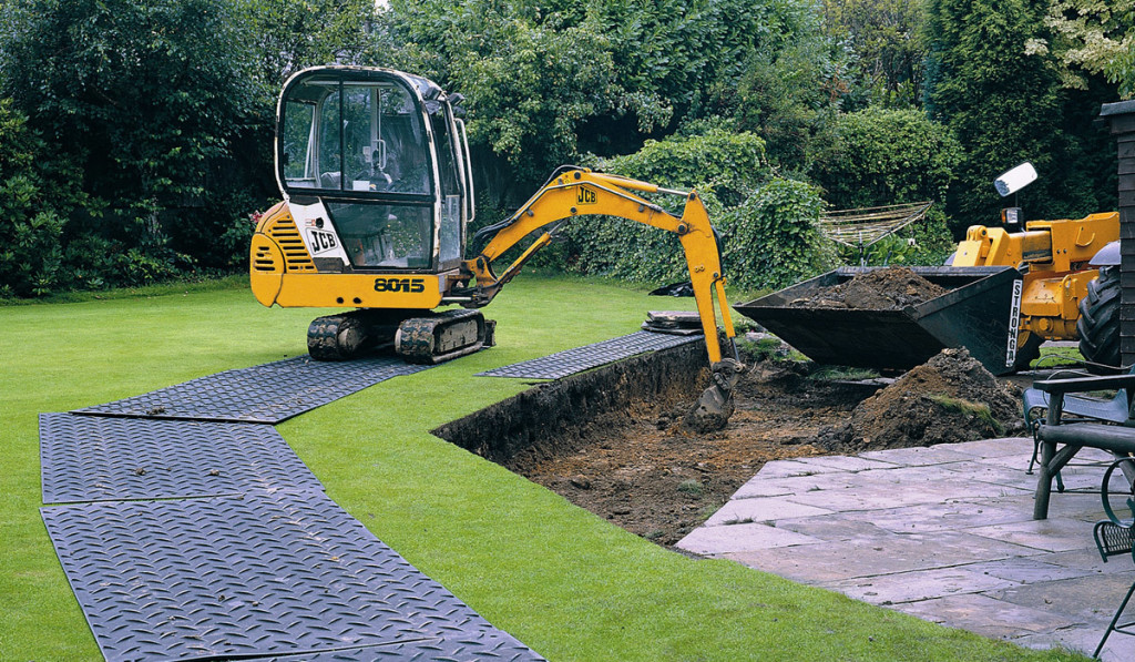 jcb digger using temporary roadway on grass in a domestic garden