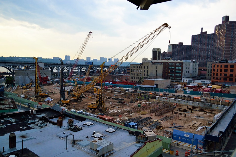 multiple cranes on building site next to buildings in the city laying foundations