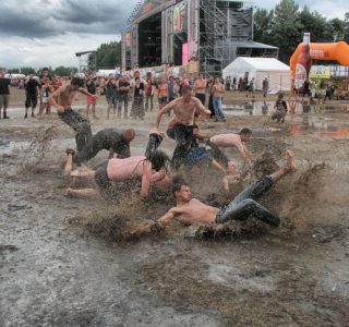Muddy woodstock festival with drenched festival goers jumping into puddles