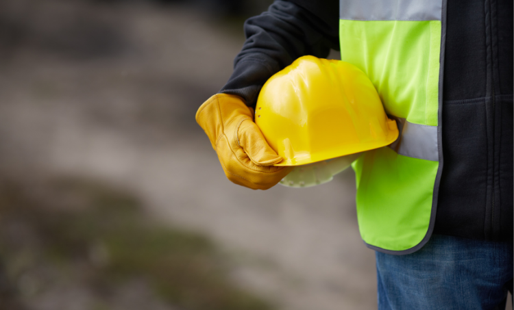 Man in high vis jacket holding a yellow hard hat.
